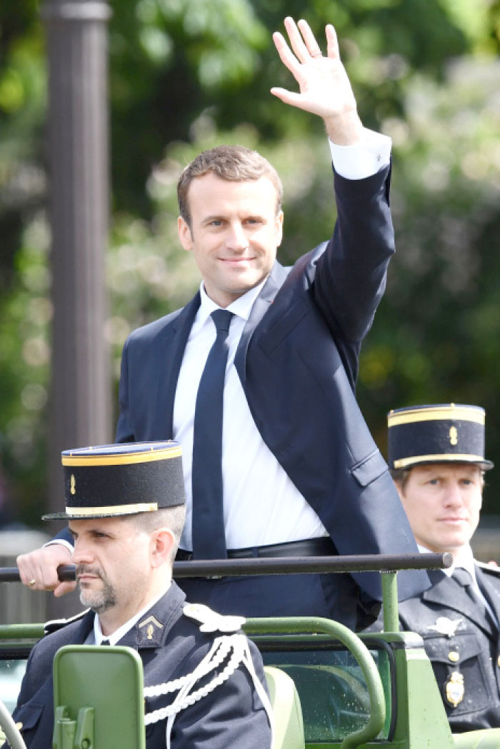French President Emmanuel Macron, center, waves as he parades in a car on the Champs Elysees avenue after his formal inauguration ceremony as French president in Paris on Sunday. — AFP