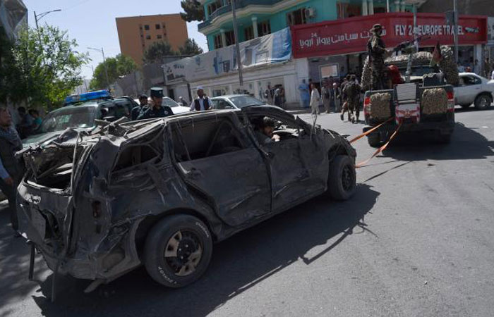 Afghan security personnel remove a damaged vehicle from the site of a car bomb attack in Kabul Wednesday. — AFP