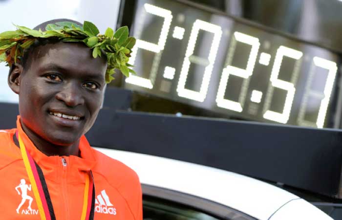 Dennis Kimetto of Kenya poses next to the timekeeping vehicle displaying his new world record, as he celebrates during the awards ceremony for the 41st Berlin Marathon on September 28, 2014. — Reuters