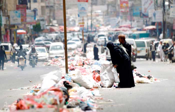 Yemenis look for items in piles of rubbish lining a road in Sanaa after sanitation workers went on strike over weeks of unpaid wages. — AFP