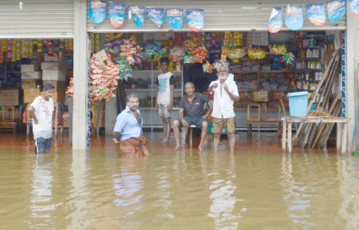 Sri Lankan residents look on from a shop surrounded by floodwaters in Nagoda in Kalutara district on Monday. — AFP
