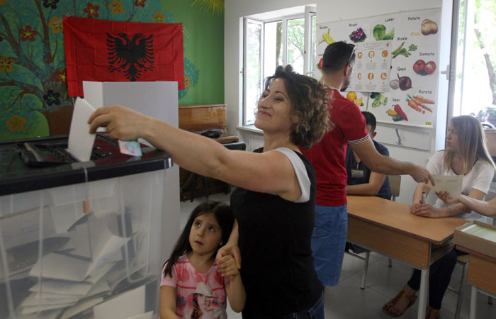 A woman casts hers ballot during the parliamentary election as her children look on at a polling station in Tirana, Albania, on Sunday. — Reuters