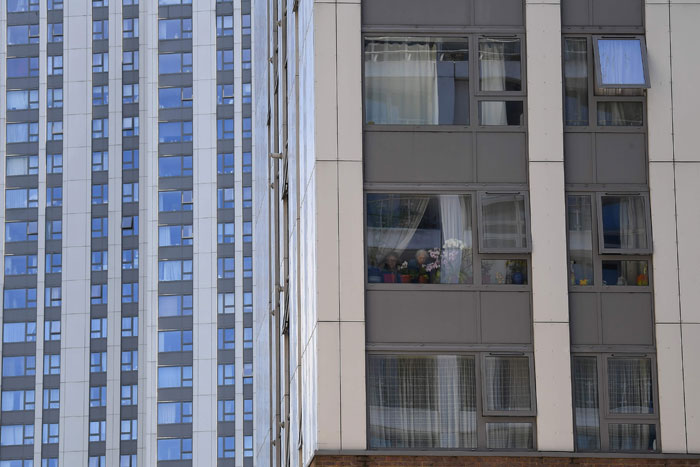 Residents look out from a window in the Taplow Tower residential block on the Chalcots Estate in north London on Monday. Six-hundred apartment blocks in England alone are believed to have the same cladding as Grenfell Tower, after the panels were widely blamed for the spread of a deadly fire there. — AFP