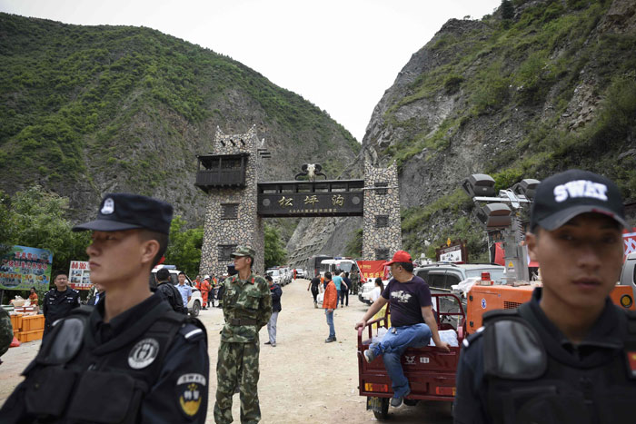 Police stand their guard at an entrance of a road to a landslide area in the village of Xinmo in Maoxian county, China's Sichuan province on Saturday. — AFP