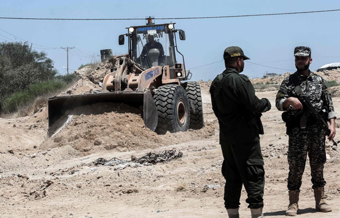 Palestinian security forces loyal to Hamas stand by as bulldozers clear an area for a large buffer zone on the border with Egypt in the southern Gaza strip town of Rafah, on Wednesday. — AFP