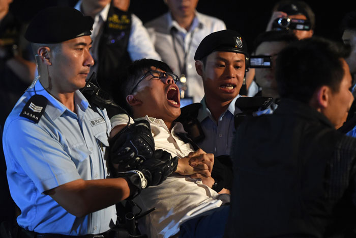 Pro-democracy campaigner Joshua Wong (C) yells as he is taken away by police after he and other demonstrators staged a sit-in protest at the Golden Bauhinia statue, given to Hong Kong by China to mark the 1997 handover, in front of the Convention and Exhibition Centre in Hong Kong on Wednesday. — AFP