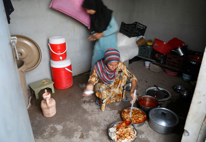 A displaced Iraqi woman from Mosul prepares food for her family's Iftar, during the Muslim holy month of Ramadan at a refugee camp Al-Khazir in the outskirts of Erbil, Iraq on Friday. AFP