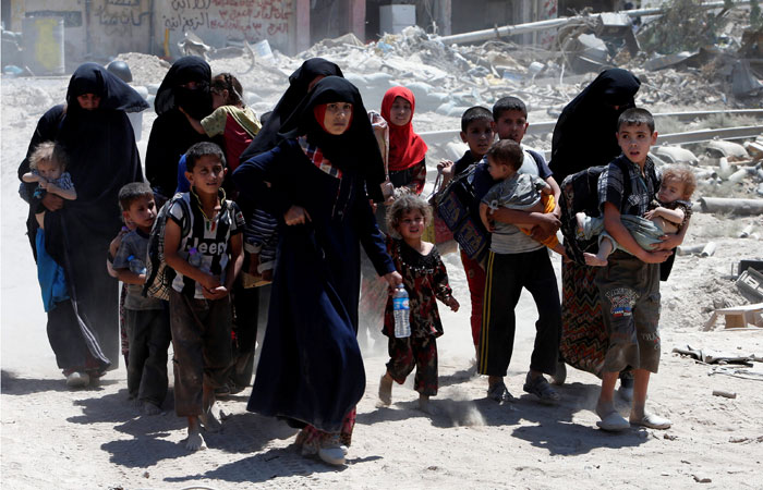Displaced women and children who fled from clashes walk in the Old City of Mosul, Iraq, on Saturday. — Reuters