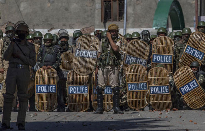 Indian paramilitary soldiers watch from a distance as they clash with Kashmiri protesters during a protest in Srinagar, Indian controlled Kashmir, on Friday. — AP