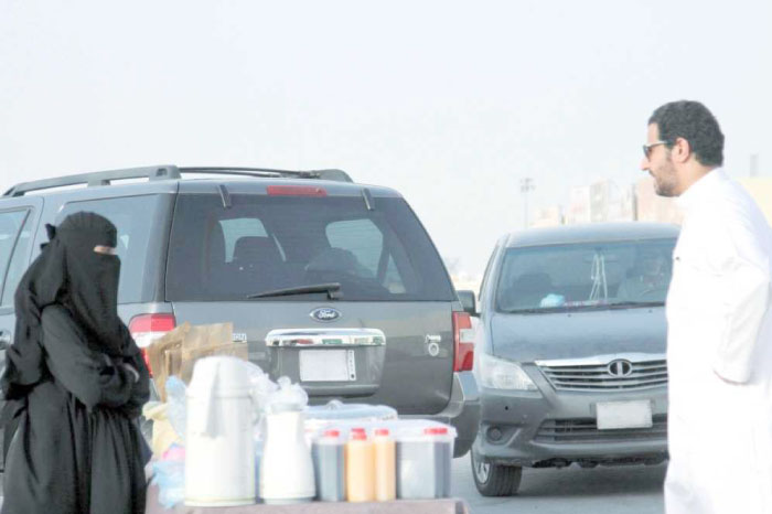 A woman displays home-made Ramadan dishes for sale on a sidewalk in Riyadh. — Okaz photo