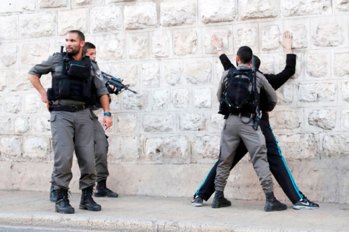 Israeli border guards search a Palestinian man outside Damascus Gate in occupied Jerusalem's Old City following an attack. — AFP