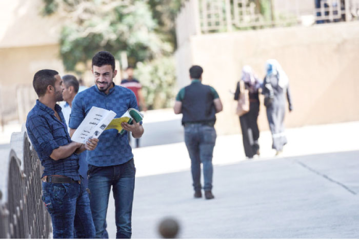 Iraqi students chat at the University of Mosul as they arrive to take their exams. — AFP