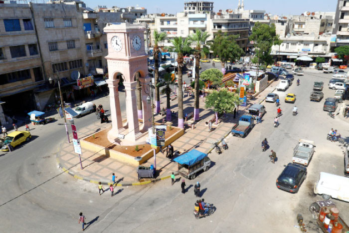 People walk around a roundabout in the rebel-held Idlib city, Syria. — Reuters