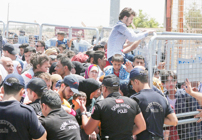 Turkish police officers try to control the order as Syrians living in Turkey push to cross into Syria at the Oncupinar border crossing, near the town of Kilis, Turkey.  — AP