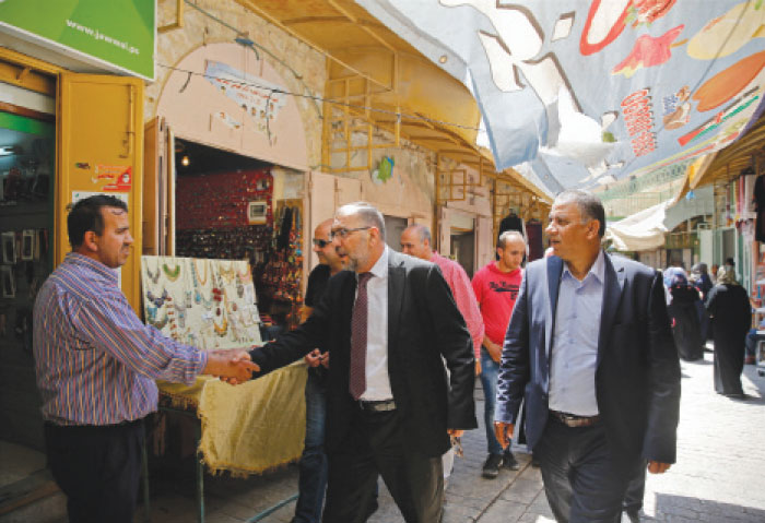 Mayor of Hebron Tayseer Abu Sneineh greets a shopkeeper at a market in the West Bank city of Hebron. For Palestinians, the new mayor of Hebron is a hero who they hope will improve their city. But to Israelis, the new leader of the divided West Bank city is an unrepentant murderer who was convicted and sentenced to life in prison as one of the gunmen in an attack in Hebron on Israeli settlers in 1980. — AP