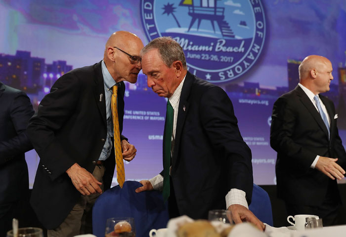 Former New York City Mayor Michael Bloomberg (C) speaks with James Carville during the United States Conference of Mayors at the Fountainebleau Hotel on Tuesday in Miami Beach, Florida.  — AFP