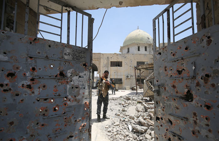 A member of the Iraqi federal police stands raising the victory gesture in the grounds of the damaged historic 19th century Ziwani mosque in the Old City of Mosul on Wednesday, as Iraqi forces inspect damage the building sustained during the offensive to retake the last remaining district from Daesh (so-called IS) group fighters. —  AFP
