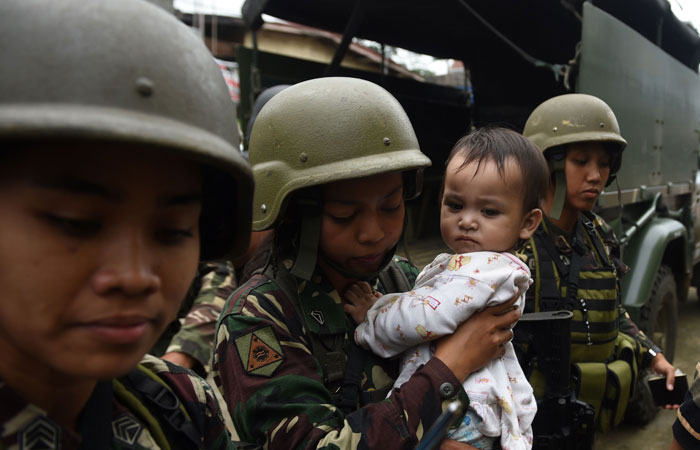 Philippine army troopers escort rescued child from ground zero of the fighting between government troops and Muslim militants in Marawi, on southern island of Mindanao on Sunday. The Philippine military declared an eight-hour ceasefire Sunday in its offensive against militants occupying parts of the war-torn city of Marawi, to allow residents to celebrate the end of Ramadan. — AFP