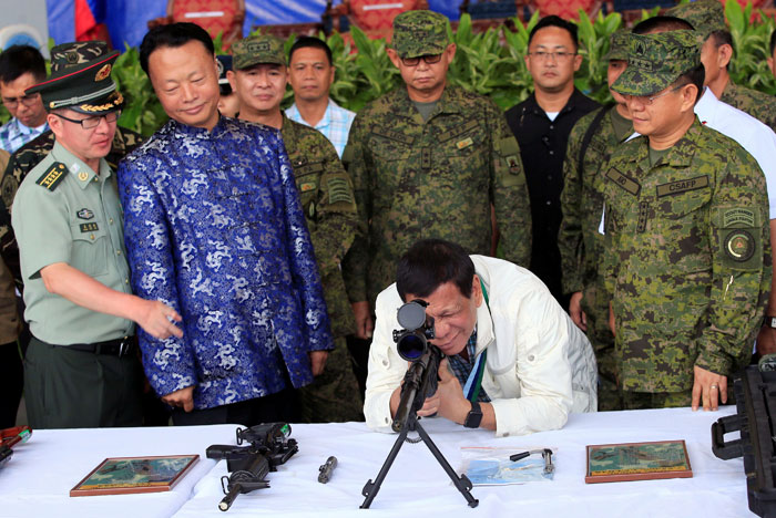 Philippine President Rodrigo Duterte checks the scope of a 7.62mm sniper rifle during the turnover ceremony of China's urgent military assistance given 