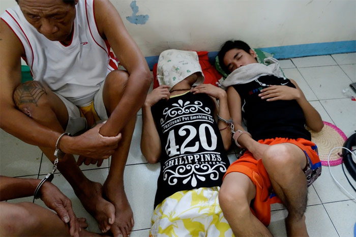 Philippine men detained on drugs charges lie on the floor of a police station in Quezon City Police District in Manila. — Reuters