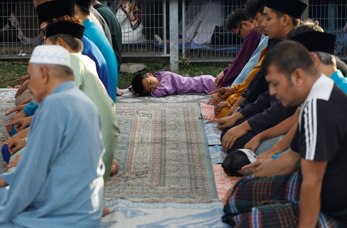 A boy looks on amongst Muslims praying during Eid Al-Fitr prayers, marking the end of the holy fasting month of Ramadan, in Singapore Sunday. — Reuters