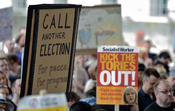 Demonstrators hold placards and chant during an anti-Conservative Party Leader and Britain's Prime Minister Theresa May, and Democratic Unionist Party (DUP) protest, on Whitehall, oppostite the enntrance to Downing Street in central London.  —  AFP