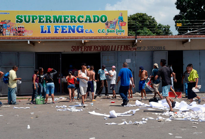 People loot a supermarket in Maracay, Aragua state, Venezuela on Tuesday. — AFP