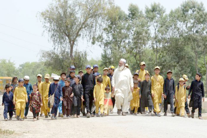 Pakistani father Gulzar Khan, center, 57, who has 36 children from his three wives, walks with his children as they return home after school in the northwestern town of Bannu in this May 20, 2017 file photo. — AFP