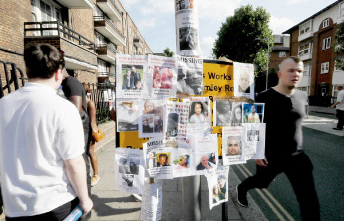Posters of people missing are stuck to a lamp post near Grenfell Tower in London on Saturday. — AP