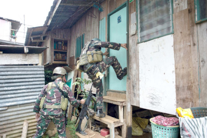 A soldier smashes a door during a house-to-house clearing operation against Islamist militants in Marawi, on the southern island of Mindanao, on Wednesday. — AFP