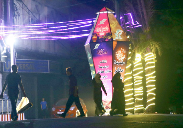 People walk along lighted road and a large traditional Ramadan lantern during the holy month of Ramadan in Gaza City, early Tuesday. — AP