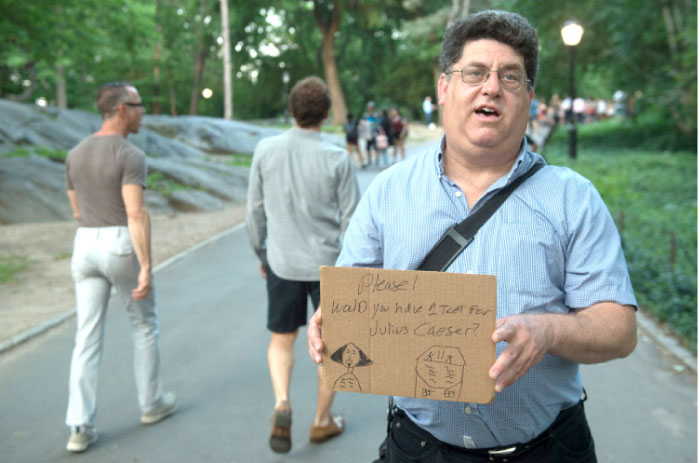 Ken Jacowitz of Queens holds a sign asking passersby for an extra ticket to opening night of Shakespeare in the Park’s production of Julius Caesar at Central Park’s Delacorte Theater in New York City on Tuesday. - AFP