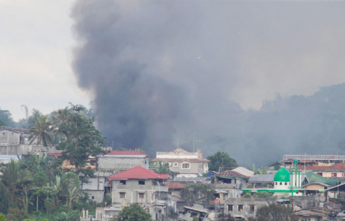 Smoke billows from a burning building in Moncado Colony village, as government troops continue their assault against insurgents from Maute group who has taken over large parts of the Marawi City, Philippines, on Tuesday. — Reuters