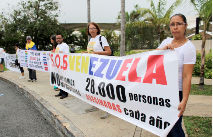 Members of the Venezuelan community hold a banner during a protest ahead of the 47th General Assembly of the Organization of American States (OAS), with Venezuela’s ongoing crisis in the spotlight, outside the international airport in Cancun, Mexico, on Monday. — Reuters