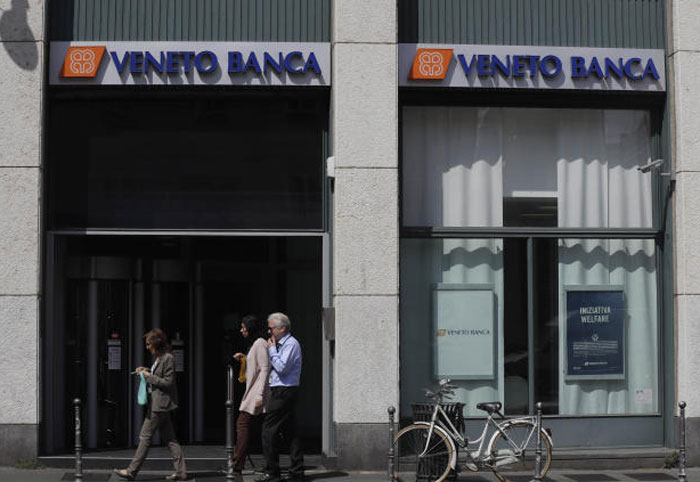 People walk past by a Veneto Banca branch in Milan, Italy, Monday, June 26, 2017. — AP